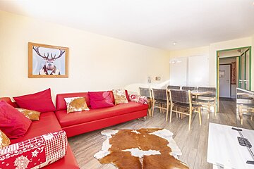 A picture of a deer hangs above a red couch