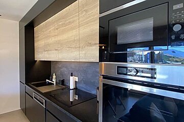 A kitchen with black cabinets and a stainless steel oven