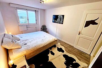 A bedroom with a cow print rug and a picture of a zebra on the wall