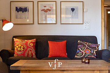 A living room with a couch and pillows and a vjp logo
