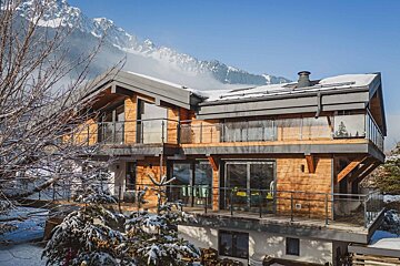 A house with snow on the ground and mountains in the background