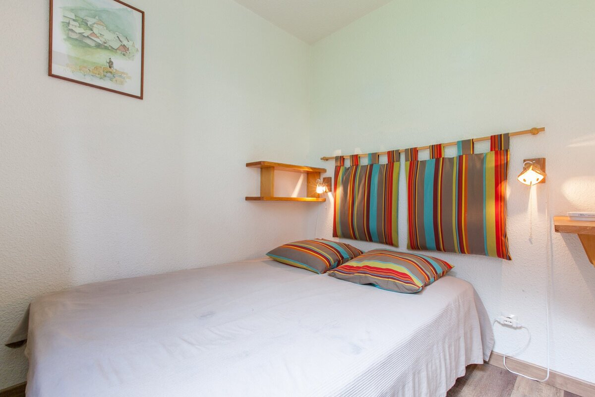 A bedroom with a bed and a picture on the wall above it