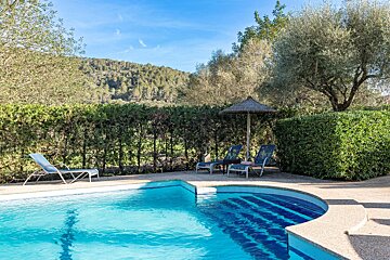 A swimming pool with chairs and an umbrella in the background