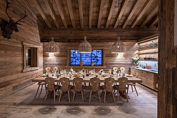 A wooden dining room with a long table and chairs