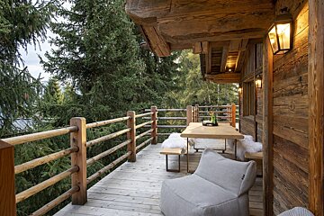 A wooden deck with a table and chairs surrounded by trees