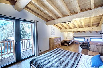 A bedroom with two beds and a balcony
