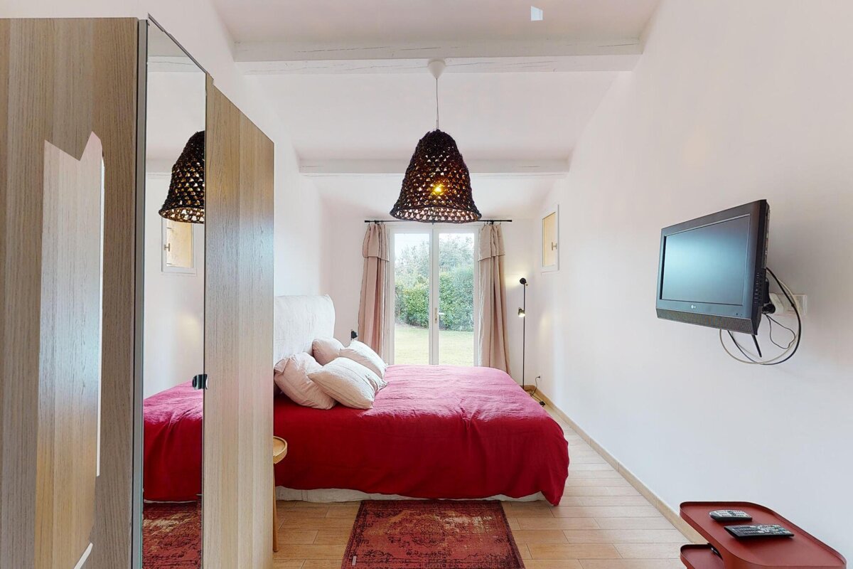 A bedroom with a red bed and a flat screen tv
