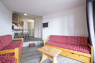 A living room with a red couch and a small table