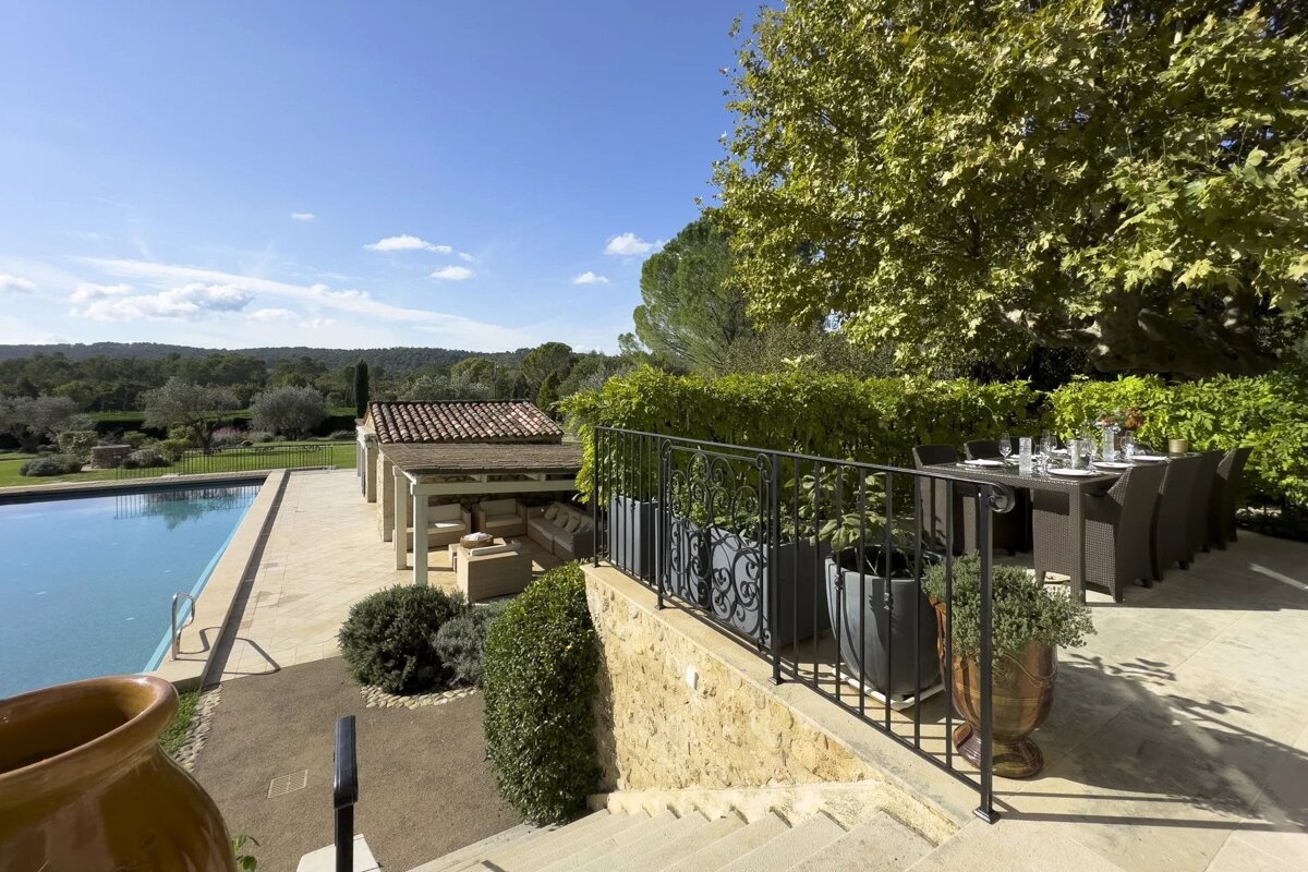 Mediterranean estate terrace featuring a swimming pool, outdoor dining area, lush greenery, and scenic valley views.
