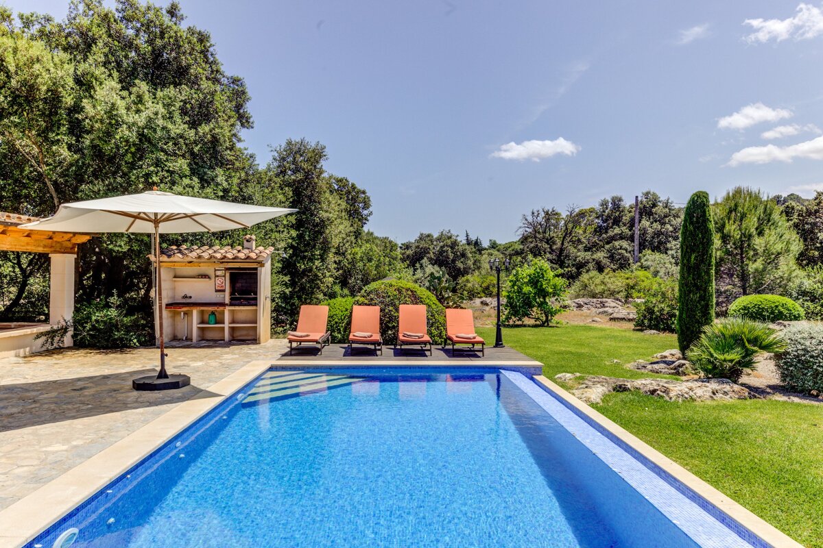 A large swimming pool surrounded by lawn chairs and an umbrella