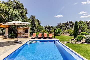 A large swimming pool surrounded by lawn chairs and an umbrella