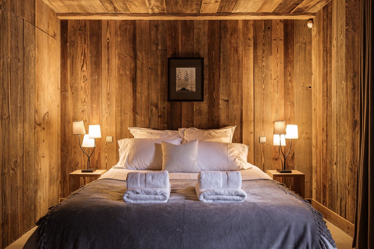 A bedroom with wood paneling and a picture on the wall above the bed