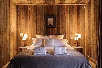 A bedroom with wood paneling and a picture on the wall above the bed