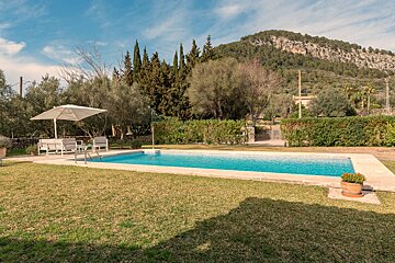 A large swimming pool with a white umbrella in the background
