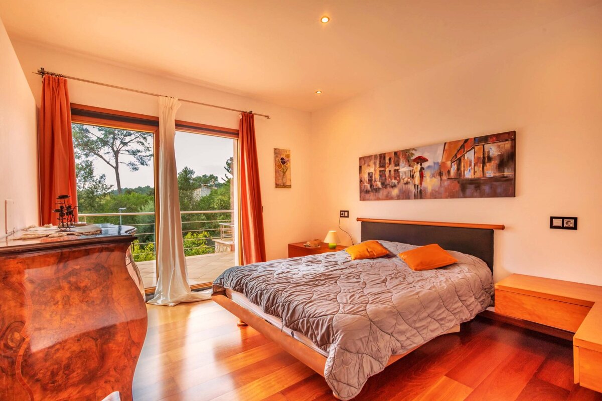 A bedroom with a painting on the wall above the bed