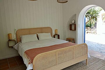 A bedroom with a wicker bed and a mirror on the wall