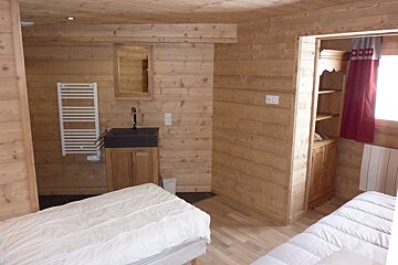 A wood-paneled room featuring two beds with white comforters, a sink with a vanity, and a wooden wall mirror.