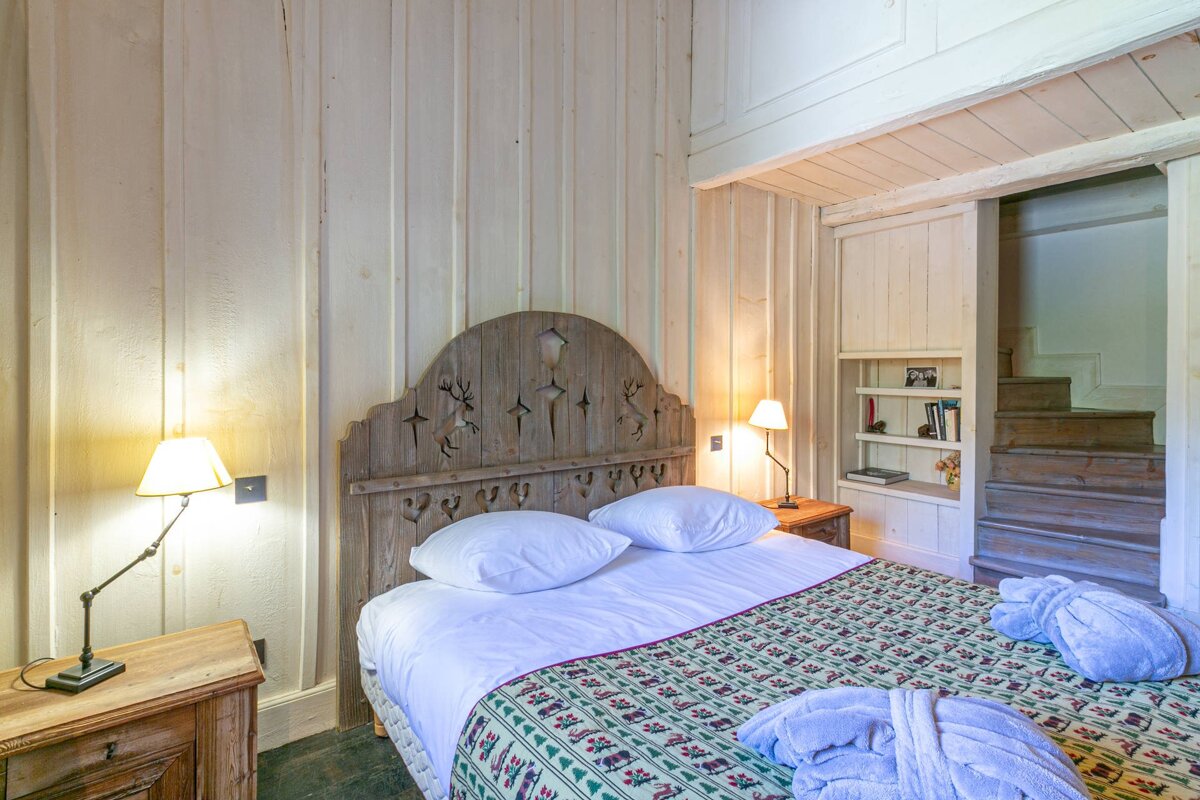 A bedroom with a bed and a wooden headboard