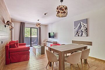 A cozy modern living/dining space features a red sofa, wooden table with cream chairs, cowhide lamps, and a mountain art piece, with a balcony view.