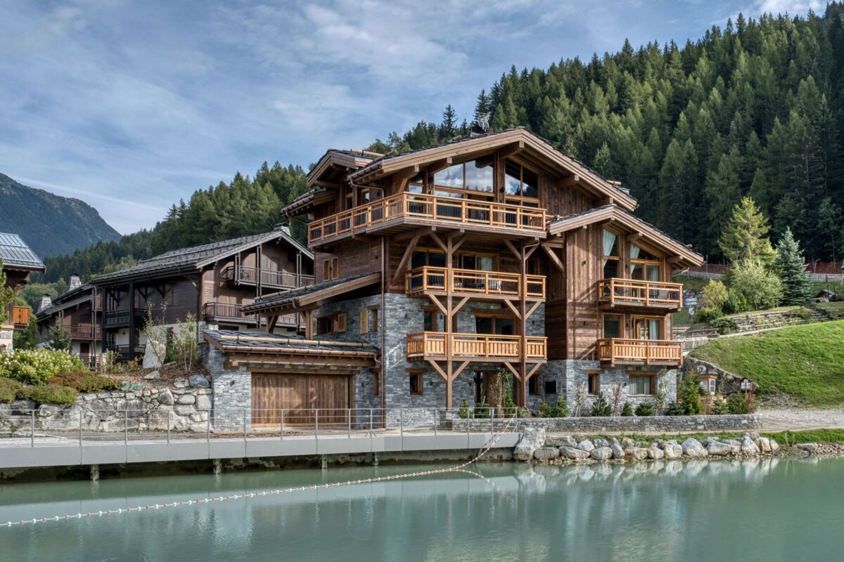 A large wooden house sits next to a body of water