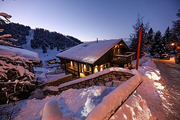 A snowy house with a red pole in front of it