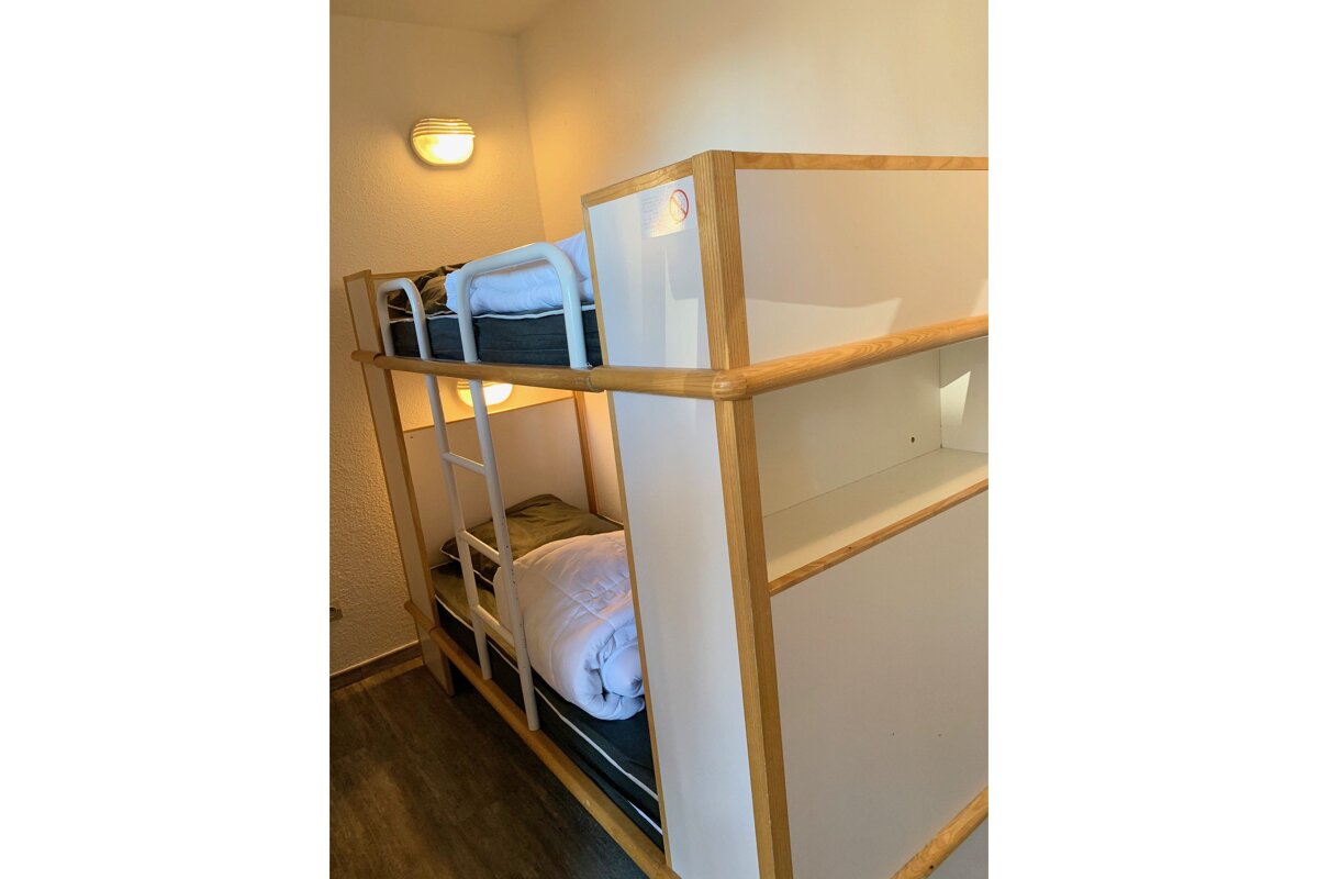A bunk bed with a ladder and a blanket on it
