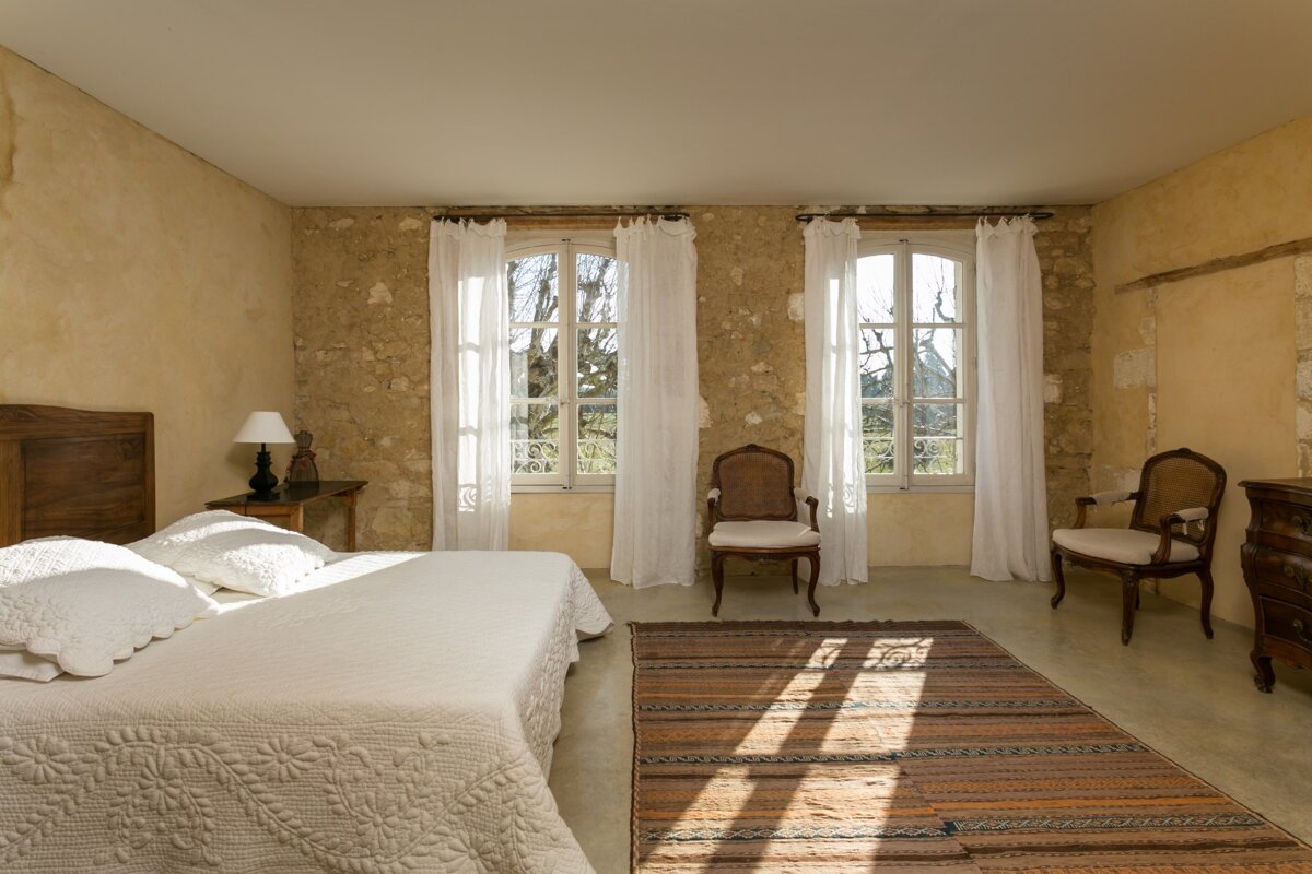 A bedroom with a large bed and two chairs
