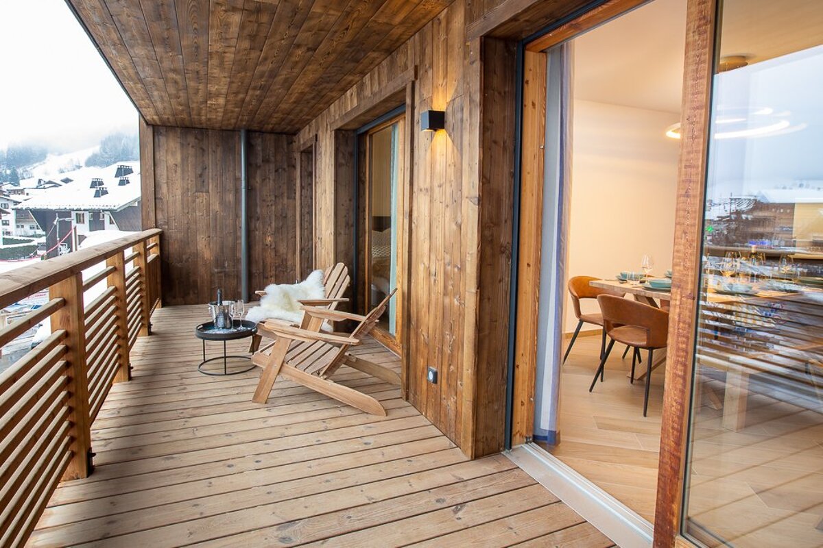 A wooden balcony with a chair and a table