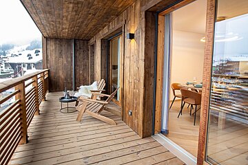 A wooden balcony with a chair and a table