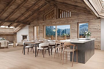 Modern wooden chalet interior featuring a dining table, kitchen island, and large windows looking out onto scenic green mountains.