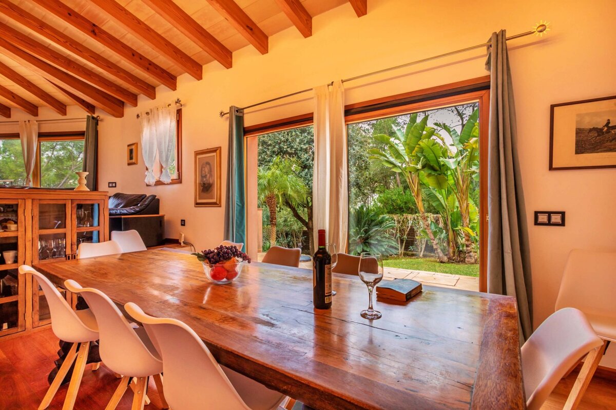 A bottle of wine sits on a wooden table in a dining room