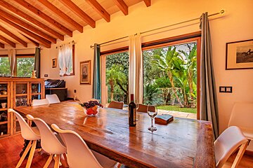 A bottle of wine sits on a wooden table in a dining room