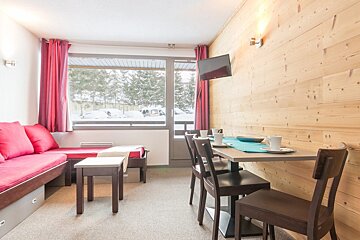 A living room with a table and chairs and a flat screen tv