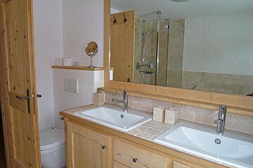 A bathroom with two sinks and a toilet