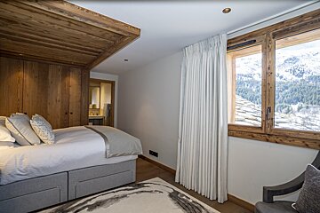 A bedroom with a bed and a window with mountains in the background