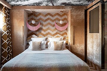A bedroom with a chevron patterned wall and a bed
