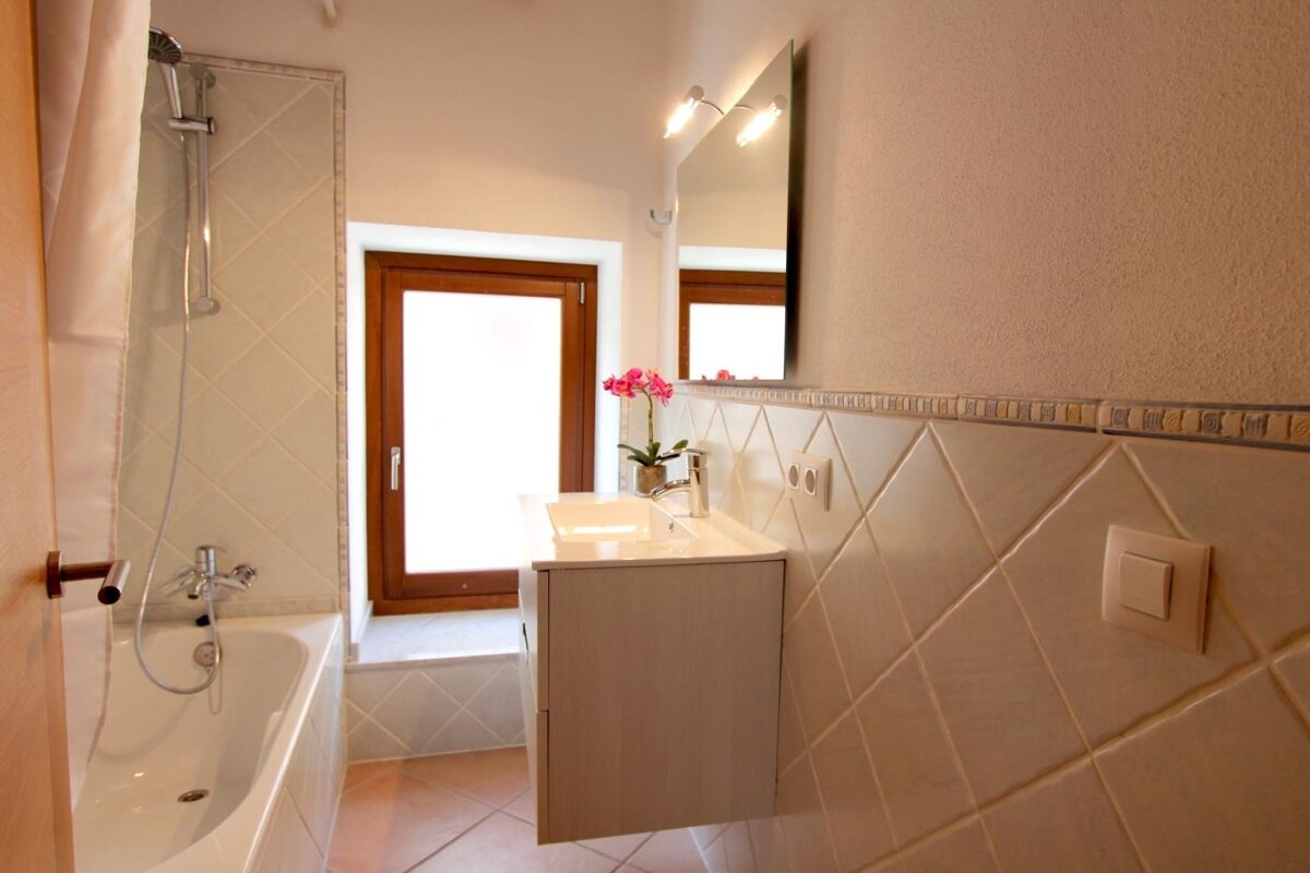 A bathroom with a bathtub sink and mirror