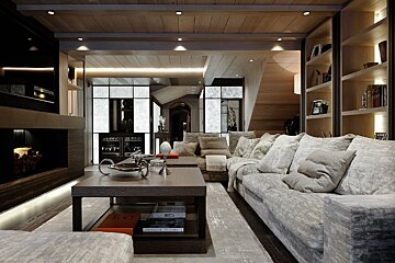 Luxurious, modern living room featuring a plush gray sofa, wooden coffee table, fireplace, and ambient lighting, in warm neutral tones.