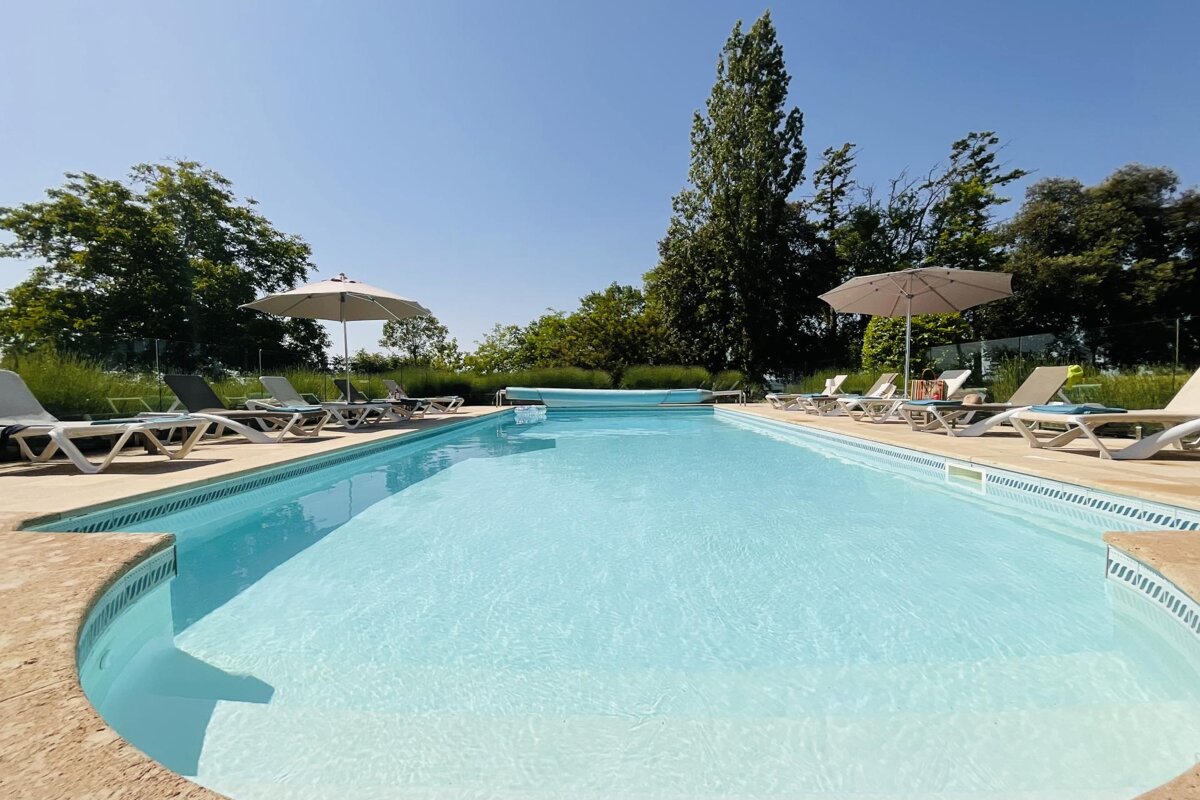 A large swimming pool surrounded by chairs and umbrellas