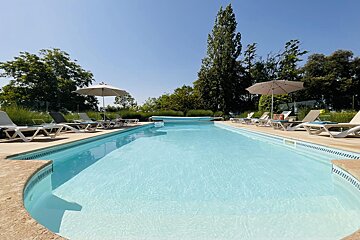 A large swimming pool surrounded by chairs and umbrellas