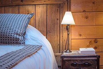 A bed with a lamp and a book on a nightstand