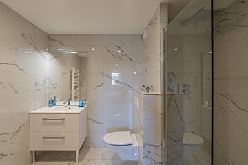 A bathroom with marble tiles and a toilet