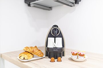 A krups coffee maker sits on a counter next to some pastries