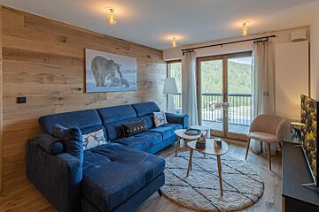 A living room with a blue couch and a picture of a polar bear on the wall