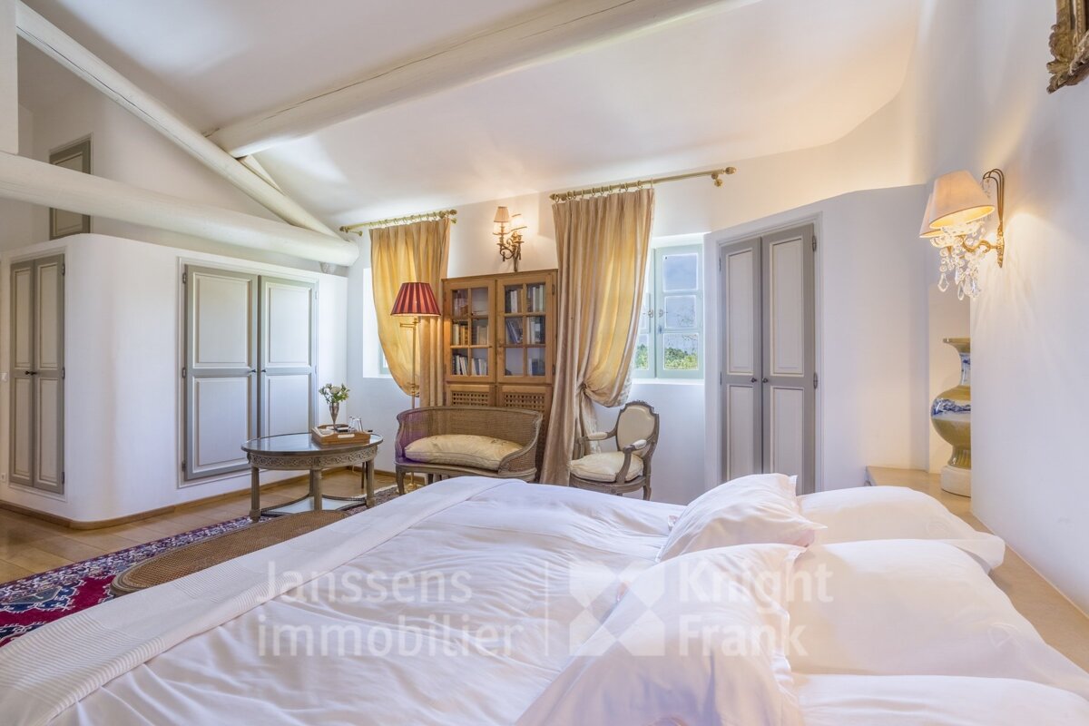 A bedroom with a large bed and a knight frank sign on the wall