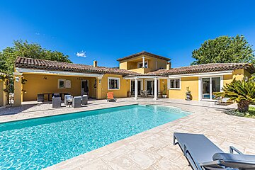 A large yellow house with a swimming pool in front of it