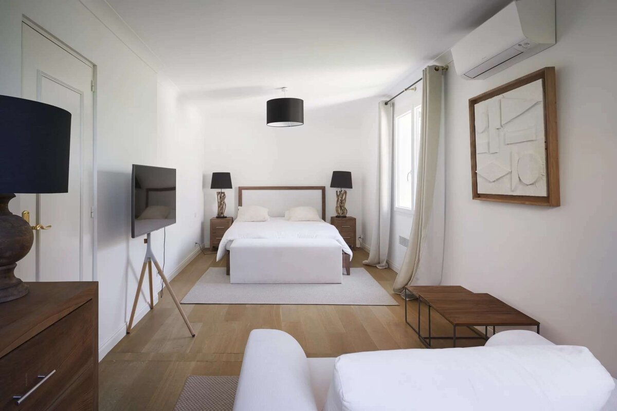 A bedroom with a bed and a television on the wall