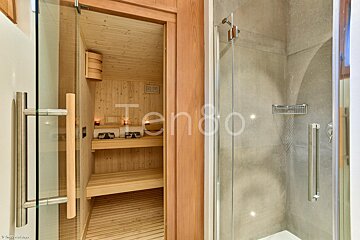 A wooden sauna is behind a glass door that says tendo
