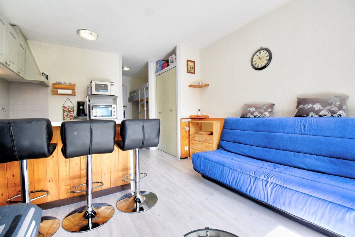 A living room with a blue couch and a clock on the wall