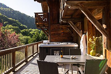 A bottle of champagne sits on a table in front of a hot tub